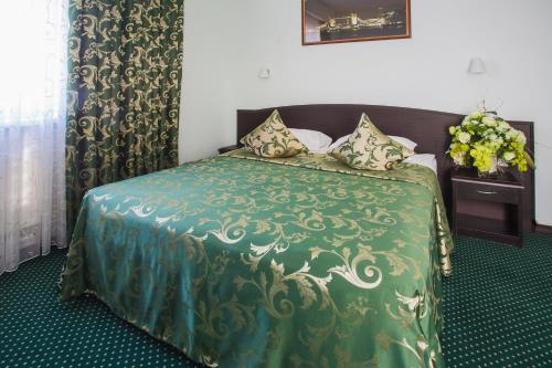 a bedroom with a bed with a green comforter at Отель Ринг Премиум in Volgograd