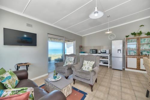 a living room with a couch and chairs and a kitchen at Marine Magic in Struisbaai