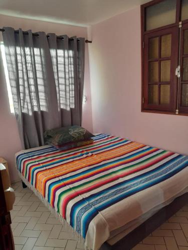 a bed with a colorful striped blanket in a room at Joli bas-de-villa in Les Abymes