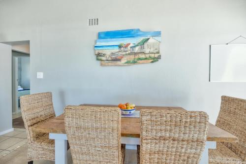 a dining room table with chairs and a painting on the wall at Marine Magic in Struisbaai