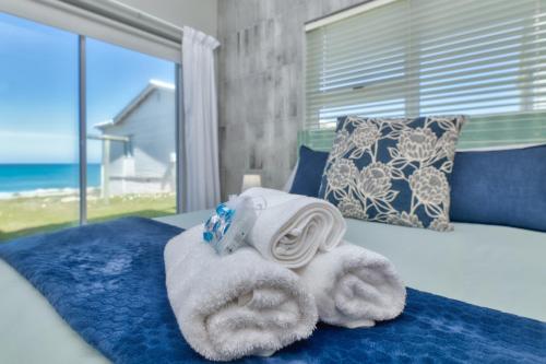 a pile of towels on a bed next to a window at Marine Magic in Struisbaai