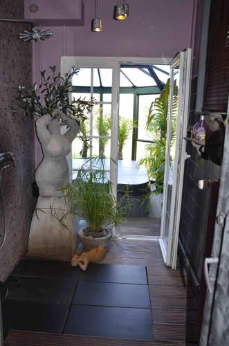 a hallway with potted plants and an open door at Chambres d'Hôtes & SPA Le Chat Chez Qui j'Habite in Saint-Aubin-sur-Mer