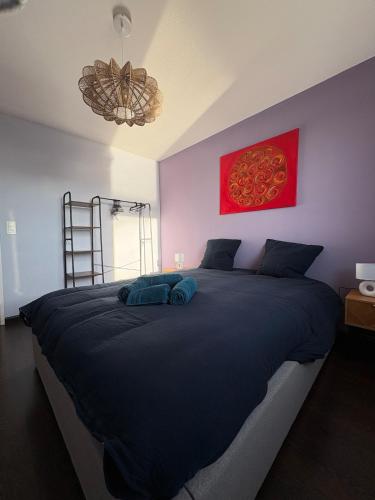 - une chambre avec un grand lit noir et une photo rouge dans l'établissement Appartement unique, coloré en Citadelle, à Dunkerque