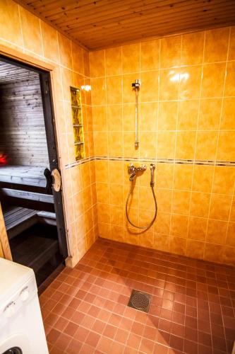 a bathroom with a shower in a yellow tiled wall at Vuokatti Apartments in Vuokatti
