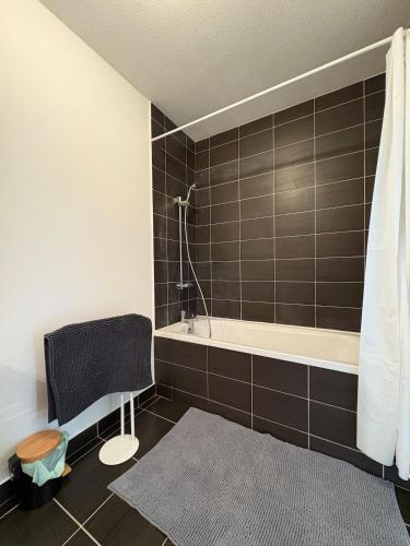 La salle de bains est pourvue d'une baignoire, d'une chaise et d'un tapis. dans l'établissement Appartement unique, coloré en Citadelle, à Dunkerque