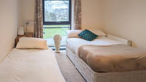 two beds in a room with a window at Modern - 1 Bed Flat in Bracknell - near airport in Bracknell