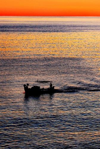a boat in the water at sunset at Sea And Sun apartments 304 Ιδιωτικό διαμέρισμα in Kardamili