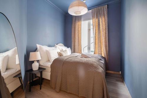 オスロにあるDINBNB Apartments Enjoy a stylish stay in the heart of the cityの青い壁のベッドルーム1室、ベッド1台、窓が備わります。