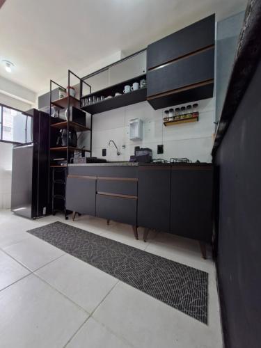 a kitchen with black cabinets and a sink at Apto térreo com ar, próximo ao shopping Caruaru com área de lazer completa! in Caruaru