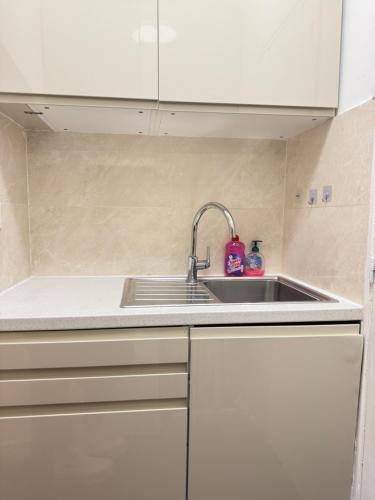 - une cuisine avec un évier et des placards blancs dans l'établissement 5 People Apt Centre Paris 3em in Meslay Marais, à Paris