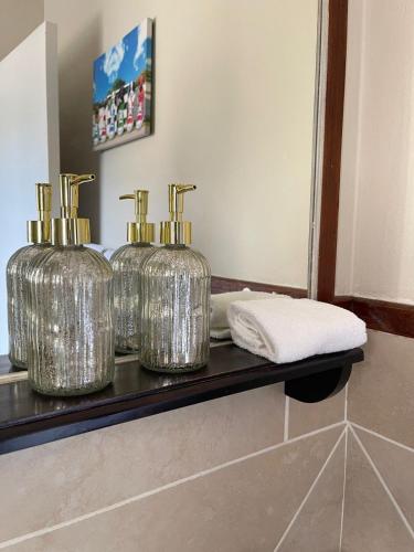 three silver containers sitting on a shelf in a bathroom at Cozy Corner in Sandton
