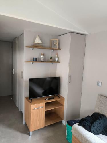 un salon avec une télévision sur un centre de divertissement en bois dans l'établissement mobil home luminosa 6pers tout équipé 3ch, à Saint-Jean-de-Monts
