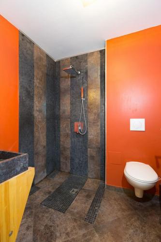 La salle de bains orange est pourvue d'une douche et de toilettes. dans l'établissement La clairière aux cerfs, à Ventron