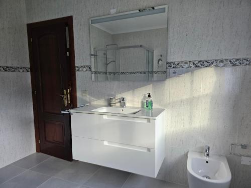 a bathroom with a sink and a mirror and a toilet at Casa Victoria - Laxe in Laxe