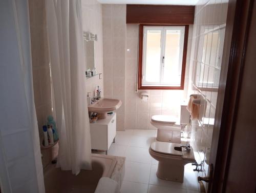 een badkamer met toilet, wastafel en raam bij Espiguiñas in Muros