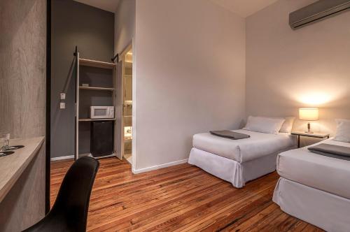 a room with two beds and a desk and a chair at Up Tribeca in Buenos Aires
