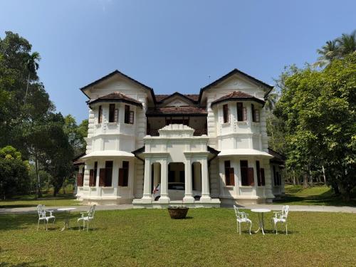a large white house with chairs in front of it at Jetwing Wahawa Walauwa, A Luxury Reserve in Rambukkana