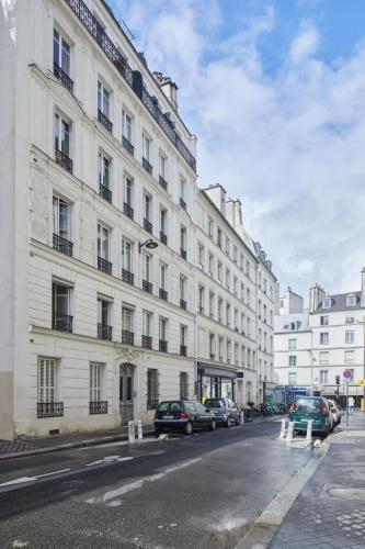 un grand bâtiment blanc avec des voitures garées devant dans l'établissement Saint-Germain-des-Prés 60m2, à Paris