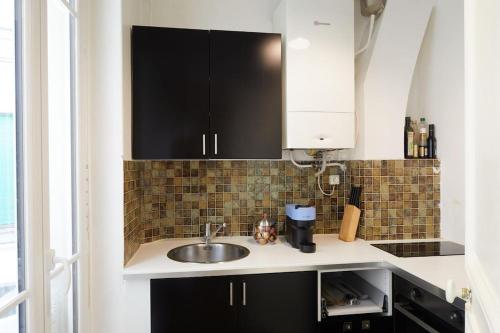 - une cuisine avec des placards noirs et un évier dans l'établissement Saint-Germain-des-Prés 60m2, à Paris