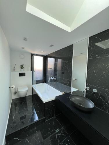 La salle de bains en noir et blanc est pourvue d'un lavabo et d'une baignoire. dans l'établissement Beautiful house in calais, à Calais