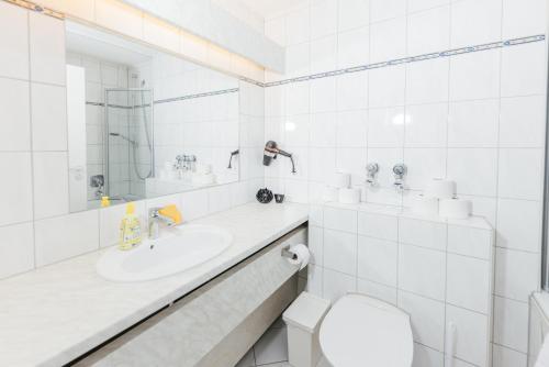 a white bathroom with a sink and a toilet at Rosenalm Scheidegg in Scheidegg