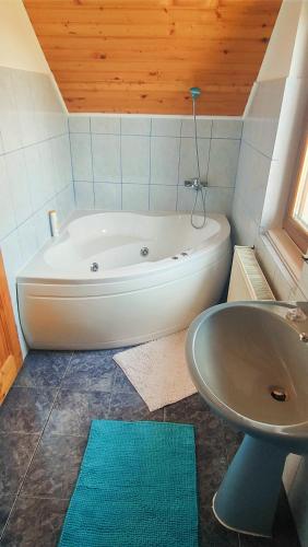 a bathroom with a white tub and a sink at Casa Ciubărului Bran in Predeluţ