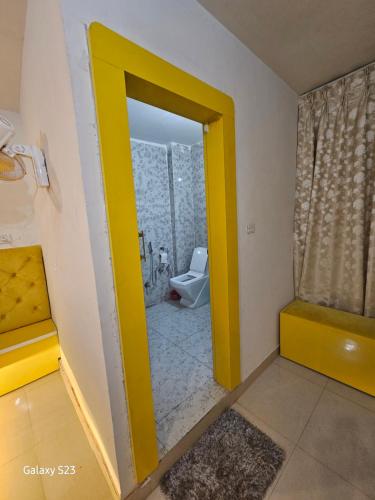 a bathroom with a yellow door and a toilet at Last Minute Deal @ Hotel Sunset in Orchha