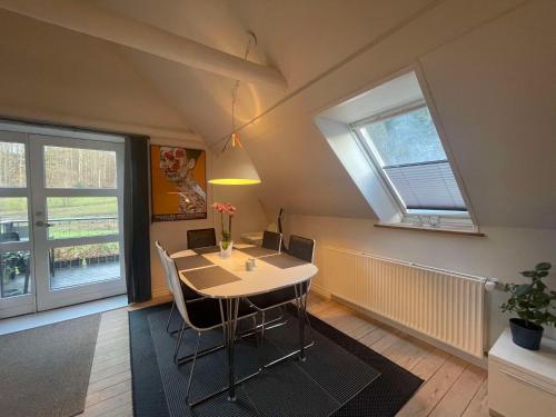 a dining room with a table and two windows at Naturskøn landidyl på Ibækgaarden - I egen bolig in Vejle