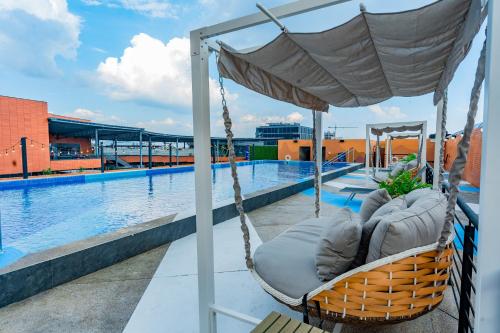 a hammock on the roof of a building with a pool at Aloft Guadalajara Sur in Guadalajara