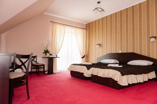 ein Schlafzimmer mit einem großen Bett und einem roten Teppich in der Unterkunft Hotel Podzamcze in Góra Kalwaria