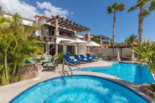 a pool in front of a house with palm trees at Vista Encantada Resort & Spa Residences, A La Carte All Inclusive Optional in Cabo San Lucas