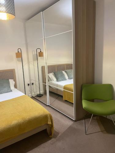 a bedroom with a bed and a mirror and a green chair at Stunning 3 bed house - Wantage in Wantage