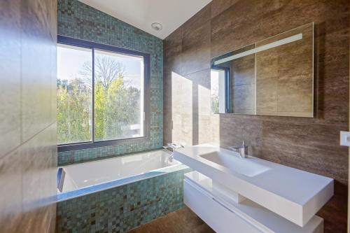une salle de bain avec une baignoire, un lavabo et une fenêtre dans l'établissement Villa Marion Biarritz - 3 suites & piscine, à Biarritz