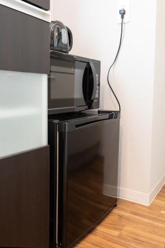 a microwave oven sitting on top of a refrigerator at Flex cella Tsukisamu in Sapporo