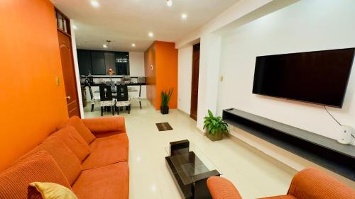 a living room with orange walls and a flat screen tv at Castellares la Puebla Hostelería Departamento in Ayacucho