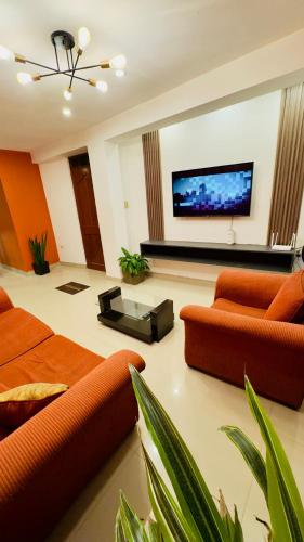 un salon avec des meubles orange et une télévision à écran plat dans l'établissement Castellares la Puebla Hostelería Departamento, à Ayacucho