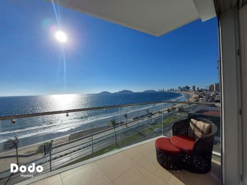 a balcony with a view of the beach and a red chair at Departamentos en Sunset View frente al malecón de Mazatlán in Mazatlán