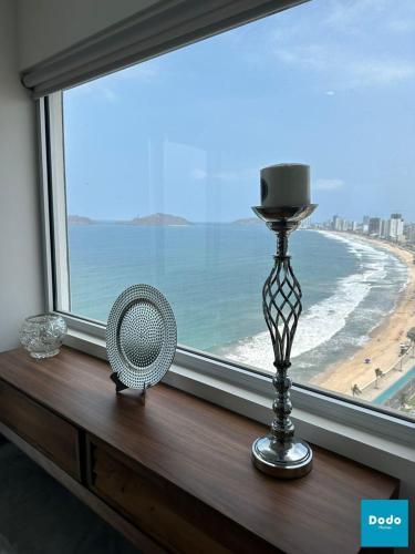 a fan sitting on a window sill with a view of the beach at Departamentos en Sunset View frente al malecón de Mazatlán in Mazatlán