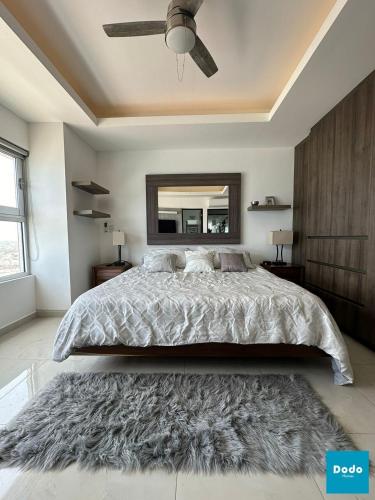 a bedroom with a large bed and a mirror at Departamentos en Sunset View frente al malecón de Mazatlán in Mazatlán