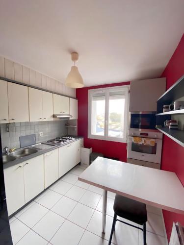 une cuisine avec une table blanche et un mur rouge dans l'établissement Appartement proche centre-ville, à Brest