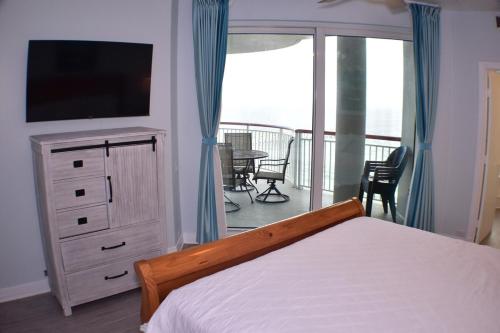 a bedroom with a bed and a television and a balcony at Beach Front Next To Pier in Navarre