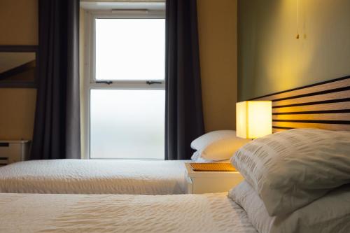 a hotel room with two beds and a window at The Dolphin Hotel & Restaurant in Pembroke Dock