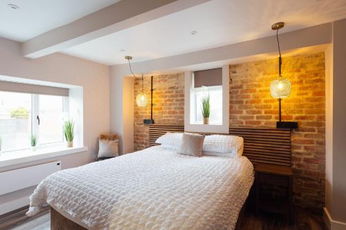 a bedroom with a bed and a brick wall at The Dolphin Hotel & Restaurant in Pembroke Dock