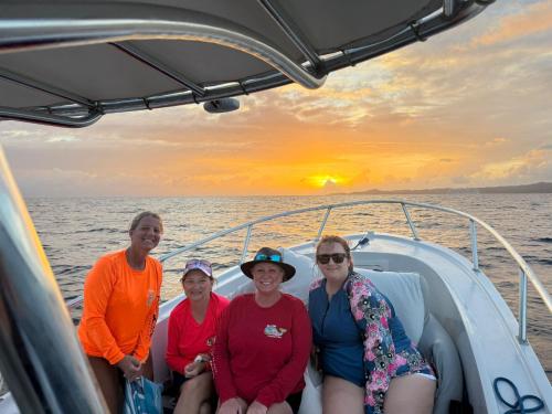 a group of women sitting on a boat at sunset at Coco View Canal lot 18 private home home in Roatan