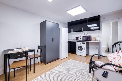 a kitchen and a living room with a table and chairs at Detached & Secluded Bungalow, Northern Line 20m to Central London, Marathon and Events ready in Colindale