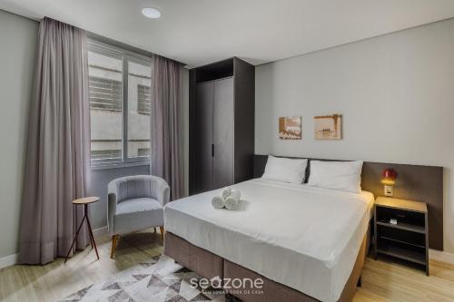 a bedroom with a large bed and a chair at TCO - Apartamentos no Centro Histórico Porto Alegre/RS in Porto Alegre