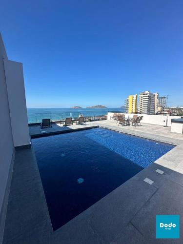 a swimming pool on top of a building with the ocean at Torre con roof garden y piscina vista al mar in Mazatlán