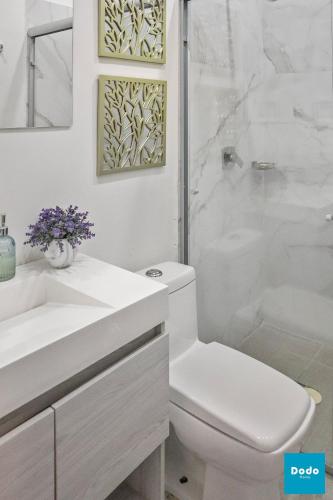 a white bathroom with a toilet and a shower at Torre con roof garden y piscina vista al mar in Mazatlán