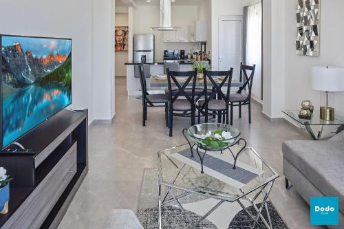 a living room with a couch and a tv and a table at Torre con roof garden y piscina vista al mar in Mazatlán