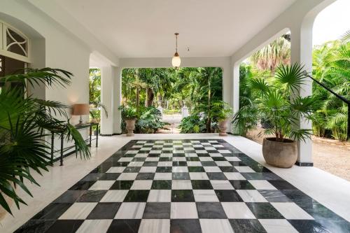 an empty lobby with a checkered floor and plants at Casa Damiana in Mérida
